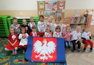 Dzieci pozują do zdjęcia z godłem Polski.