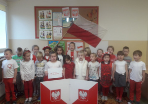 Przedszkolaki ubrani w biało-czerwone stroje, śpiewają hymn z okazji 11 listopada.