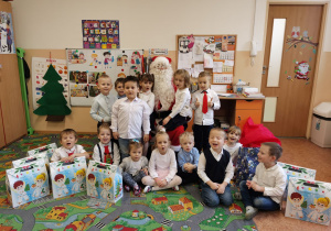 Wspólne zdjęcie dzieci z prezentami i Mikołajem.