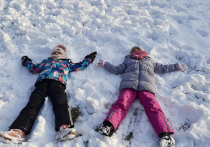 Dziewczynki robią aniołki na śniegu.