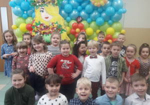 Dzieci pozują do zdjęcia grupowego przed ścianą z balonów.