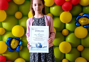 Dziewczynka z dyplomem i nagrodą za udział w konkursie.