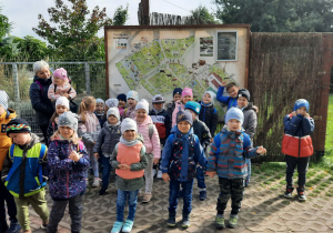 Dzieci stoją pod mapą zoo.