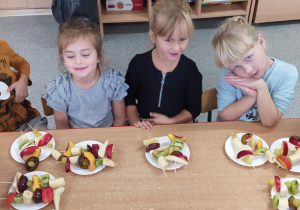 Dzieci robią szaszłyki z owoców.