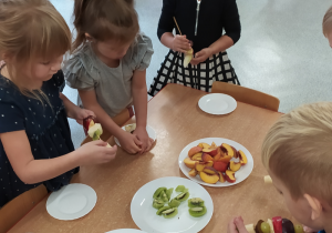 Dzieci robią szaszłyki z owoców.
