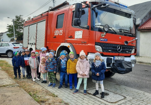 Dzieci pozują do zdjęcia przy wozie strażackim.