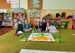 Dzieci na dywanie tworzą kwiatka żółtego z okazji dnia kobiet na macie do kodowania.