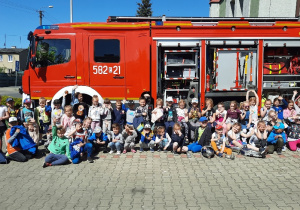 Dzieci pozują do zdjęcia przed wozem strażackim.