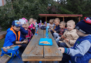 Dzieci siedzą na wozie i jedzą przekąski.