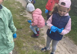 Dzieci w rękawiczkach gumowych sprzątają okolice przedszkola.