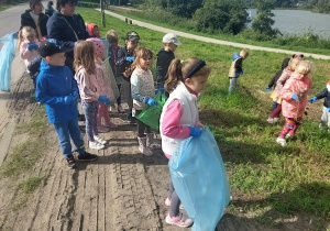 Dzieci zbierają śmieci nad ozorkowskim zalewem.