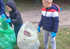 Dzieci zbierają śmieci nad ozorkowskim zalewem.