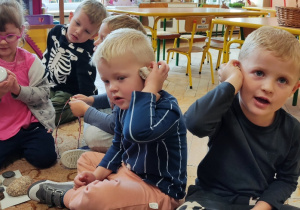Dzieci nasłuchują szumu w muszelce.