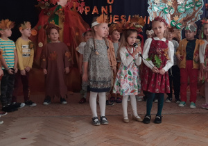 Dziewczynki ubrane w barwy jesieni mówią wiersz o jesieni.