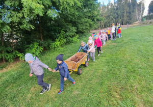 Dzieci idą na pole i ciągną wóz.