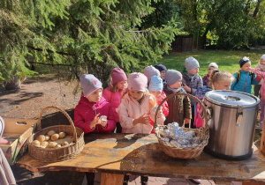 Dzieci owijają ziemniaki w folię aluminiową do ogniska.