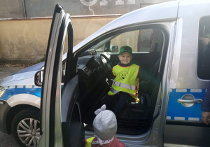 Dzieci siedzą w samochodzie policyjnym.