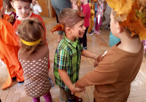 Dzieci przebrane jesiennie tańczą.
