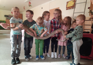 Dzieci trzymają na rękach węża.