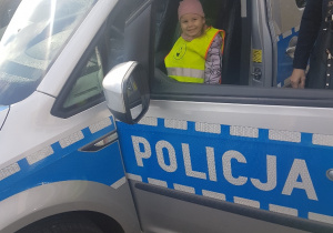 Dziecko siedzi w samochodzie policyjnym.