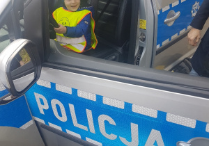 Dziecko siedzi w samochodzie policyjnym.