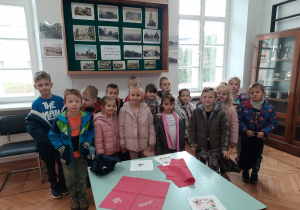 Dzieci pozują do zdjęcia przez eksponatami z wystawy o Ozorkowie.