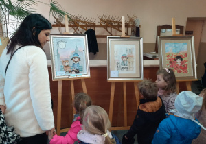 Dzieci oglądają dzieła malarskie na wystawie.
