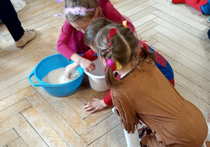 Dzieci przebrane za postacie z bajek przesypują ryż w ramach konkursu.