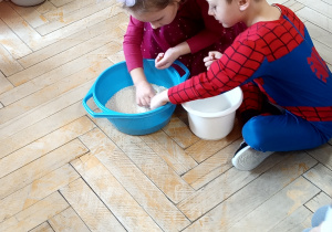 Dzieci przebrane za postacie z bajek przesypują ryż w ramach konkursu.