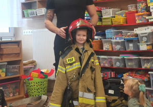Strażak przymierze dzieciom swój strój.