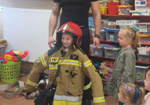 Strażak przymierze dzieciom swój strój.