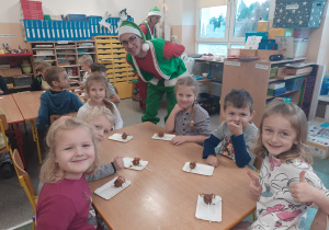 Dzieci przy stolikach, wraz z Elfem tworzą pyszności - słodkości.