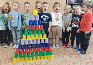 Dzieci tworzą konstrukcję z kolorowych kubeczków.