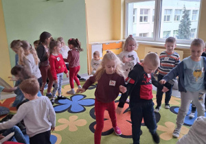 Dzieci bawią się na kolorowym dywanie w jednej z sal.