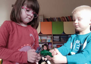 Dziewczynka z chłopcem bawią się dinozaurami.