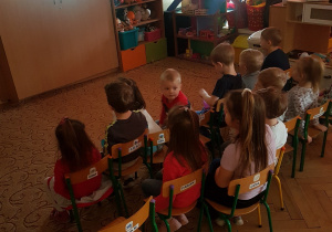 Dzieci oglądają bajkę siedząc na krzesełkach odgrywając rolę widowni w kinie.