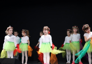 Dziewczynki w zielonych spódniczkach tańczą taniec z chusteczkami.