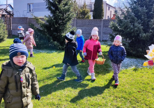 Dzieci szukają prezentu od zajączka na placu przedszkolnym.