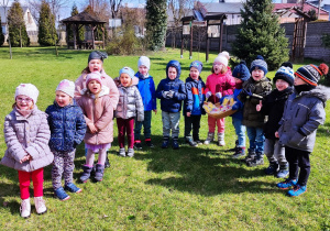 Dzieci szukają prezentu od zajączka na placu przedszkolnym.