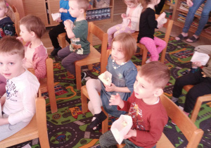 Dzieci oglądają bajkę i jedzą popcorn.