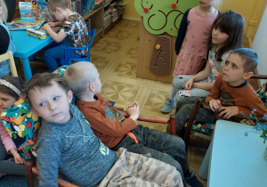 Dzieci siedzą i słuchają informacji na temat biblioteki.