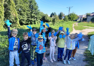 Dzieci w rękawiczkach niebieskich sprzątają świat.