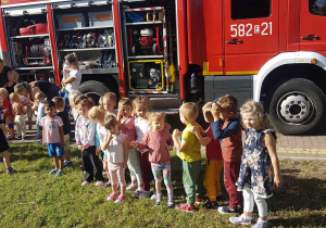 Dzieci po alarmie oglądają wóz strażacki.