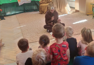 Dzieci słuchają wiersze czytane przez młodzież ze szkoły.