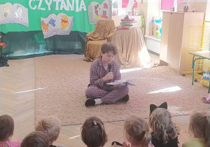 Dzieci słuchają wiersze czytane przez młodzież ze szkoły.