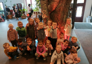 Dzieci stoją przy magicznym drzewie w teatrze.