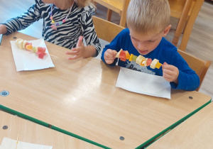 Dzieci przygotowują owoce na szaszłyki.