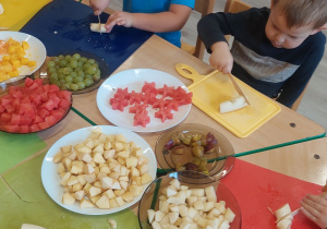 Dzieci przygotowują owoce na szaszłyki.