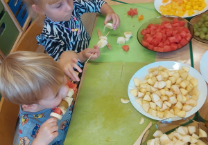 vDzieci przygotowują owoce na szaszłyki.
