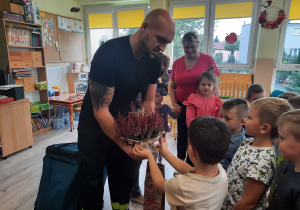 Dzieci wręczają strażakowi kwiatka w ramach podziękowań.